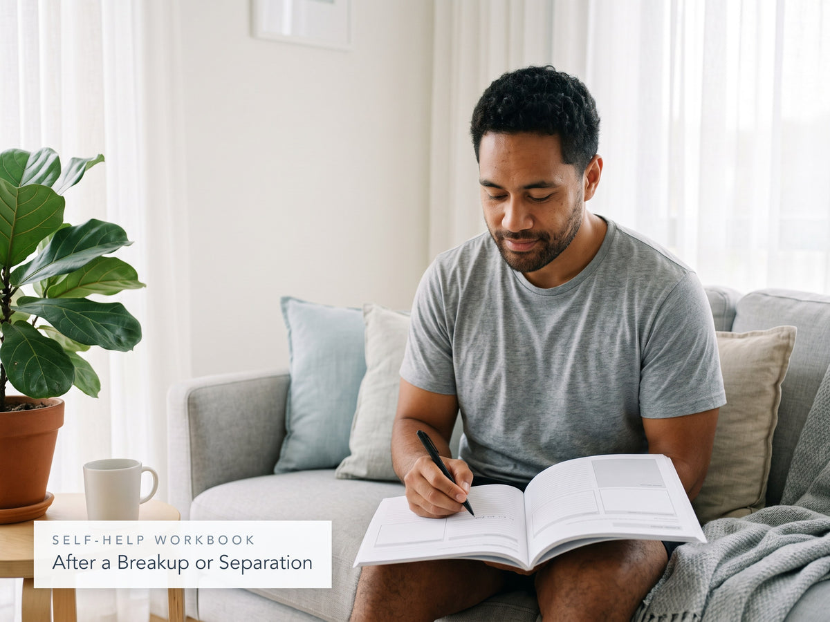 Man on a sofa writing in the After a Breakup or Separation workbook